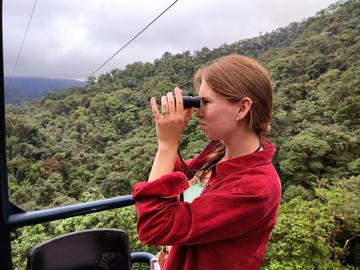 Oxford student Ruth Arnold in an aerial photo of the Choco canopy, on an expedition day in the 2km long cable car at Mashpi Reserve. At this moment, Ruth had located a Choco Toucan in a Magnolia tree opposite the camera. This photo captures a common theme