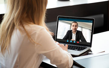 Over-shoulder view of woman on a video call with a man